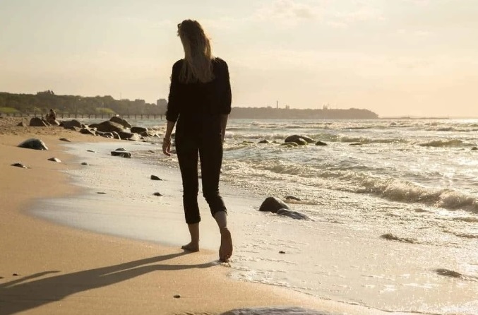 الصدمة النفسية امرأة تمشي على الشاطئ